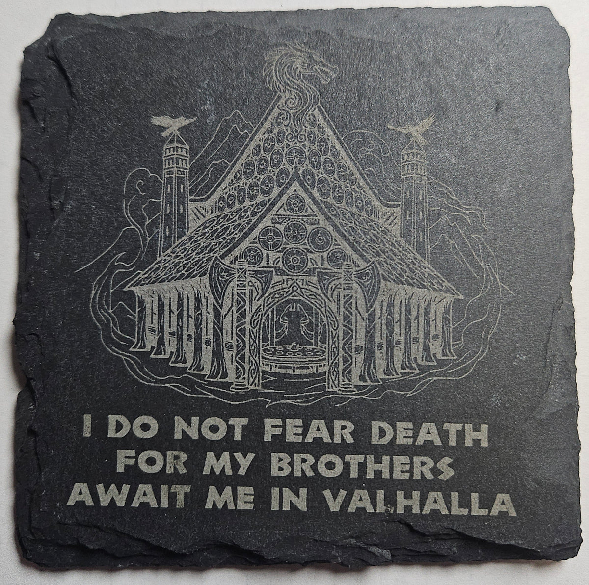 Decorative stone with Norse design and text that reads "I do not fear death for my brothers await me in Valhalla" on a gray background