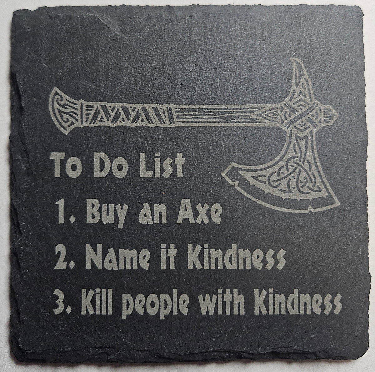 Slate coaster with axe design and humorous 'To Do List' text the reads "1. Buy an Axe 2. Name it Kindness 3. Kill people with Kindness"
