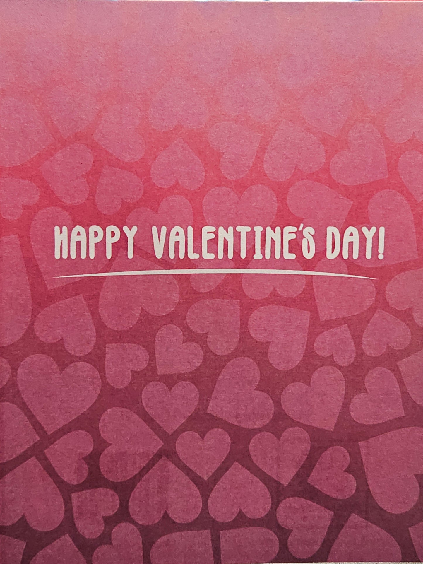 Pink card with heart pattern and 'Happy Valentine's Day!' text on a blurred background