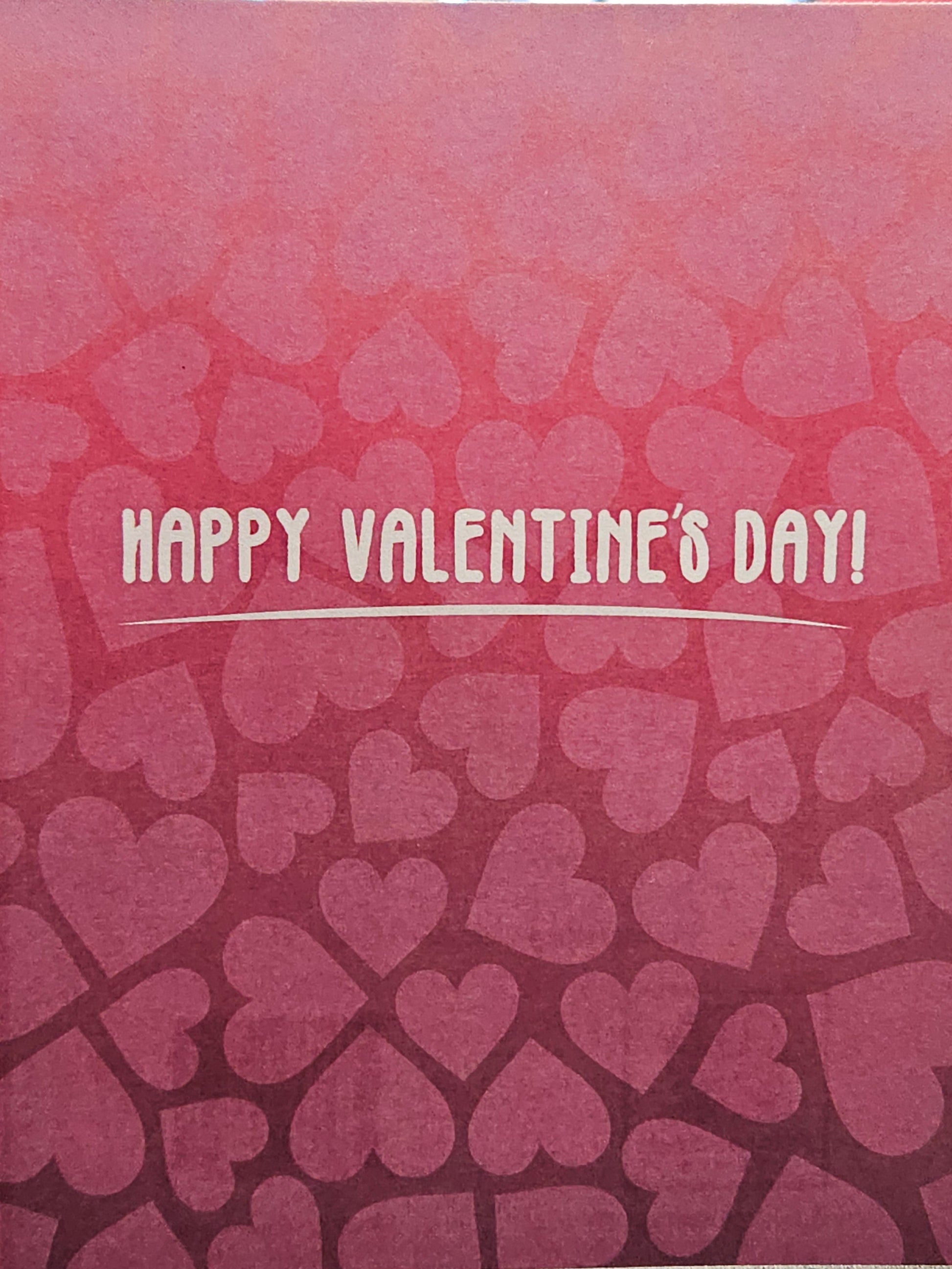 Pink card with heart pattern and 'Happy Valentine's Day!' text on a blurred background